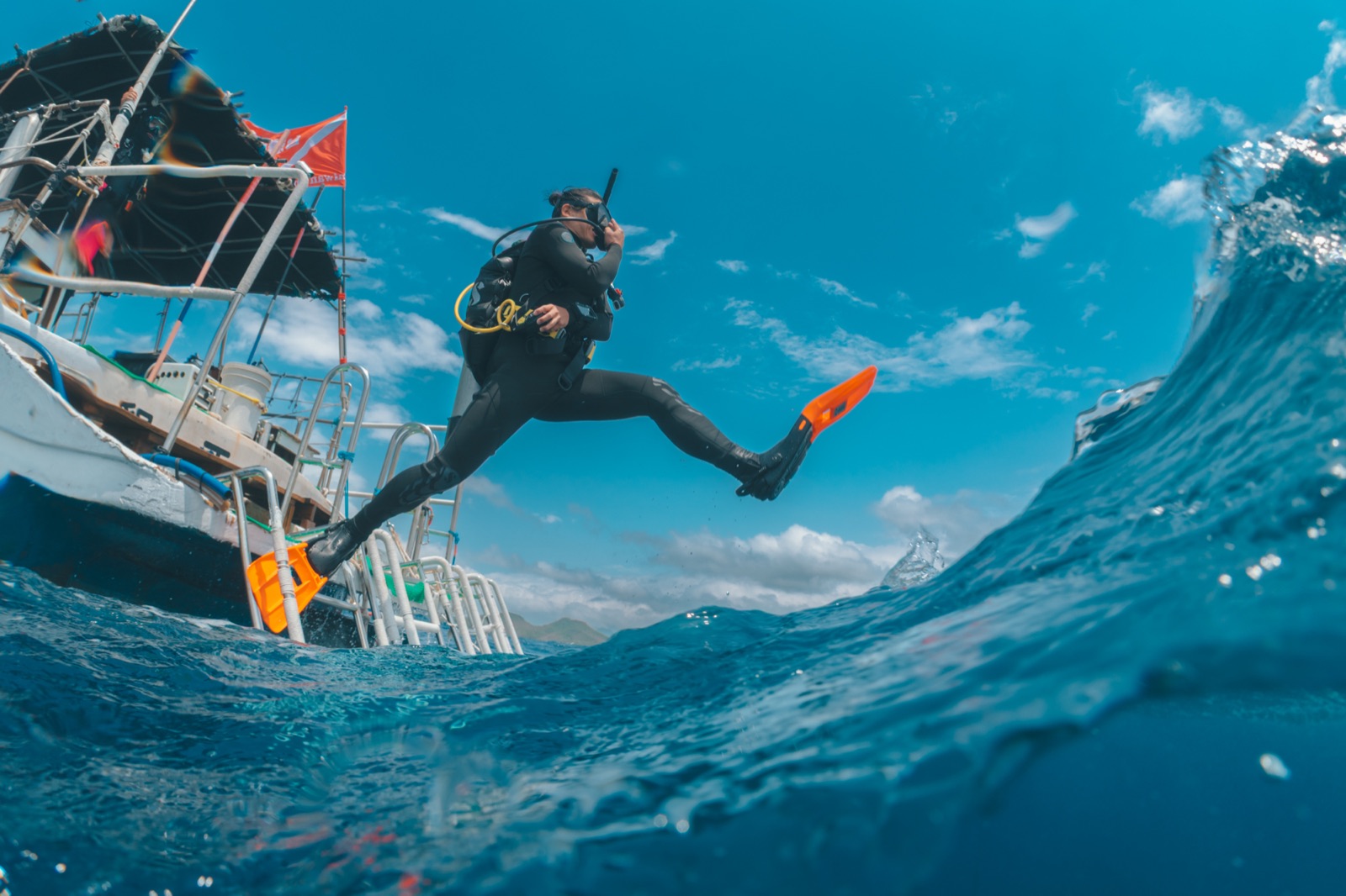 A diver stepping off a boat into the open sea